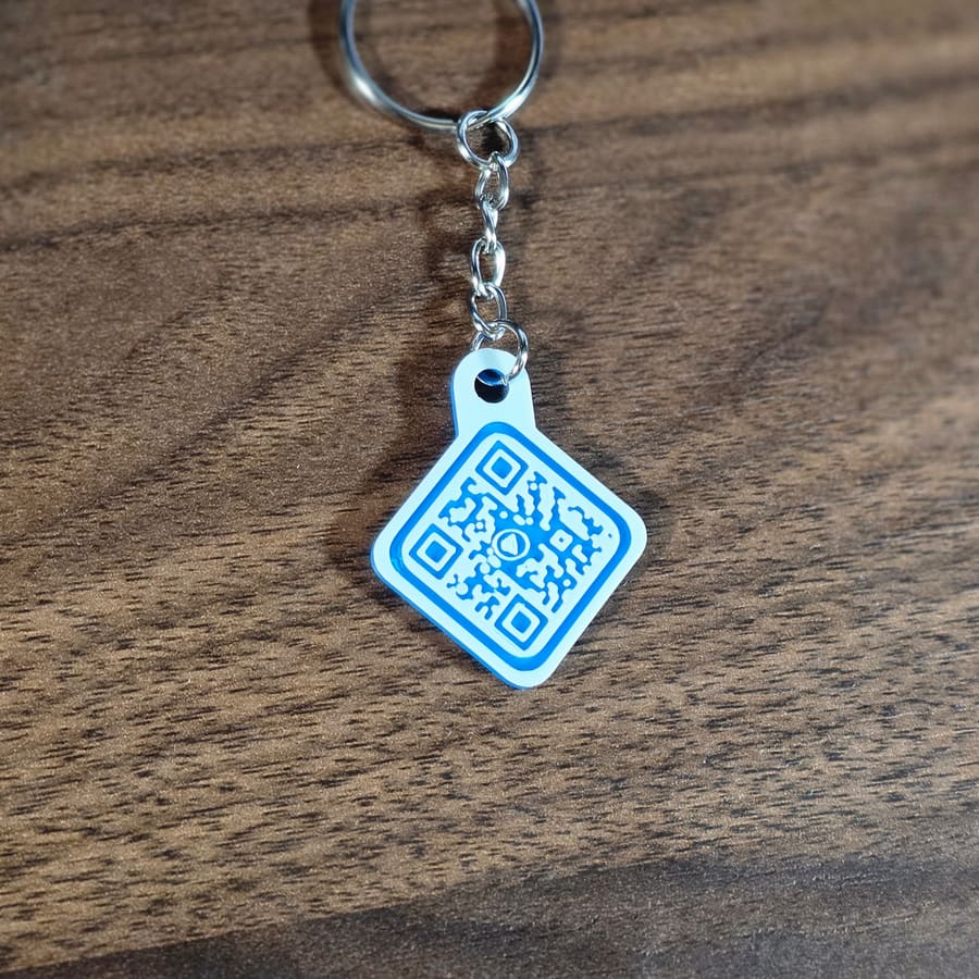Blue QR code keychain hanging on a wood background