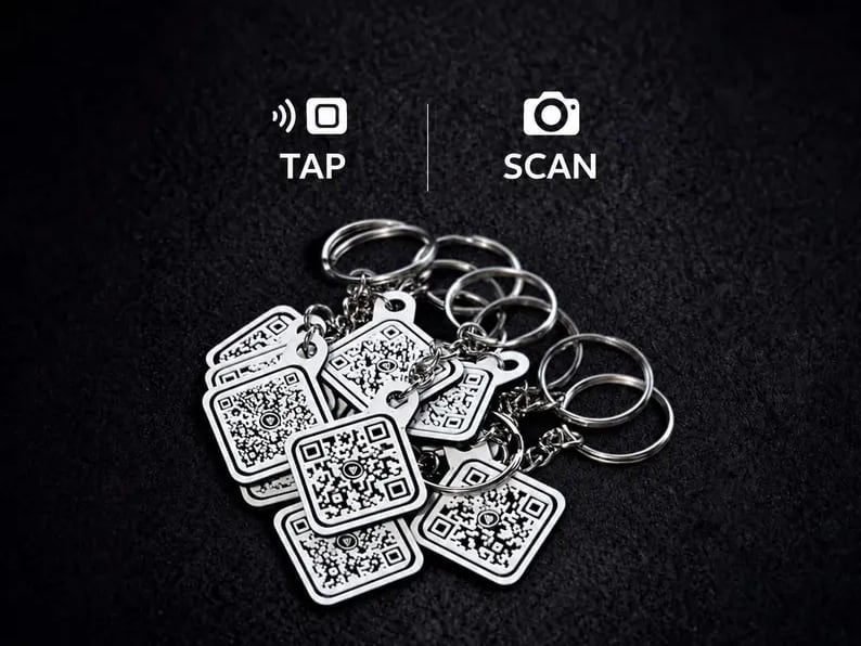A pile of white QR code keychains with split rings, below tap and scan icons