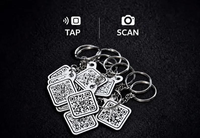 A pile of white QR code keychains with split rings, below tap and scan icons